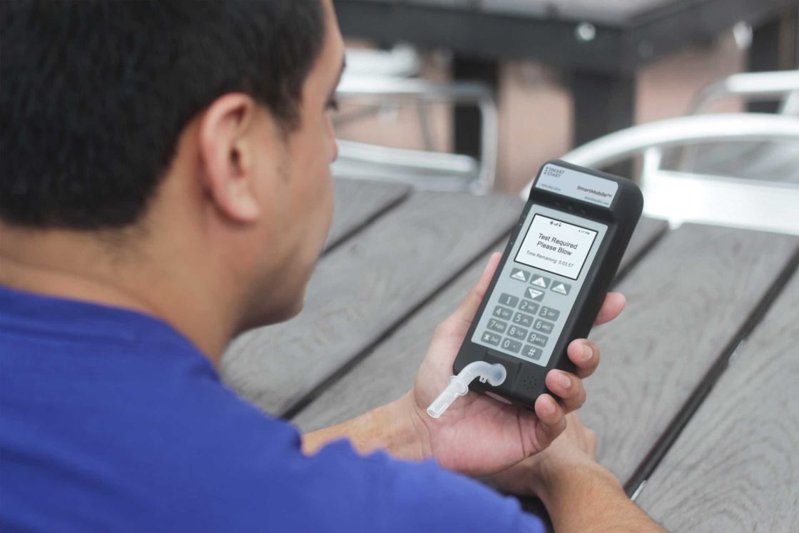 Man blowing into a Smart Mobile monitoring device outdoors